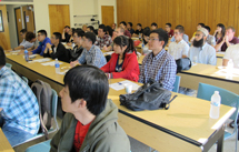 Graduate students sitting at desks listening to information presented during graduate orientation