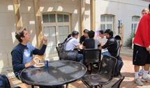 Students eating pizza sitting at tables and talking at the student alumni mixer