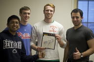 Four students posing with a circuit board